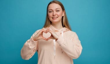 Smiling young blonde woman making a love sign that symbolizes a healthy heart