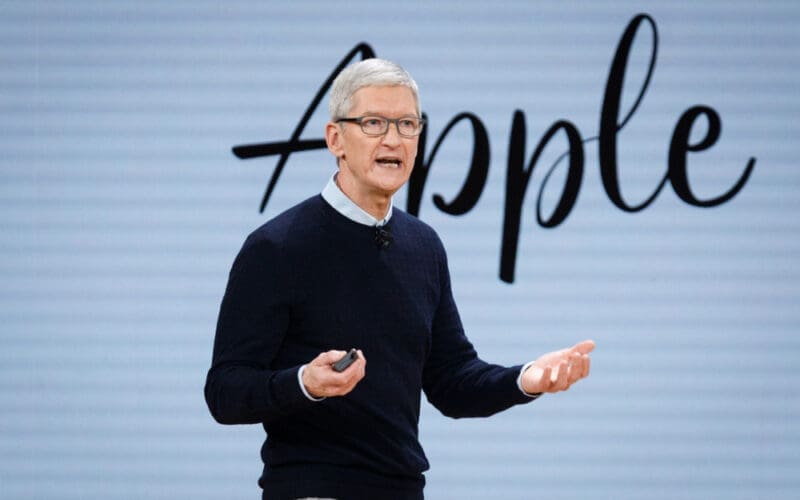 Apple CEO Tim Cook speaks on stage with a microphone and a remote in his hands