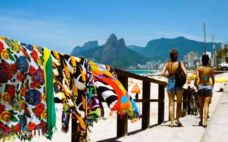 Two women stroll toward Ipanema Beach in Rio de Janeiro on a sunny day