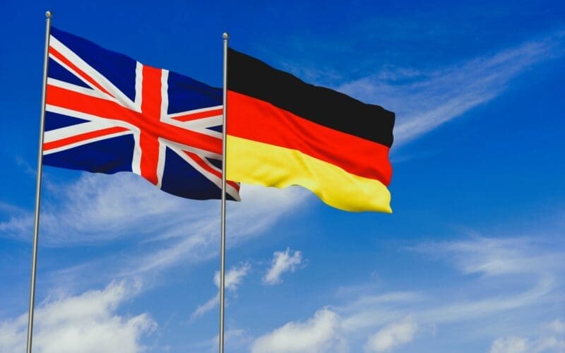 United Kingdom and Germany flags over blue sky background