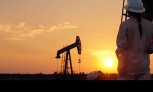 Worker and oil rig against the backdrop of a sunset