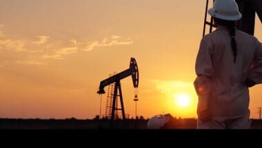 Worker and oil rig against the backdrop of a sunset