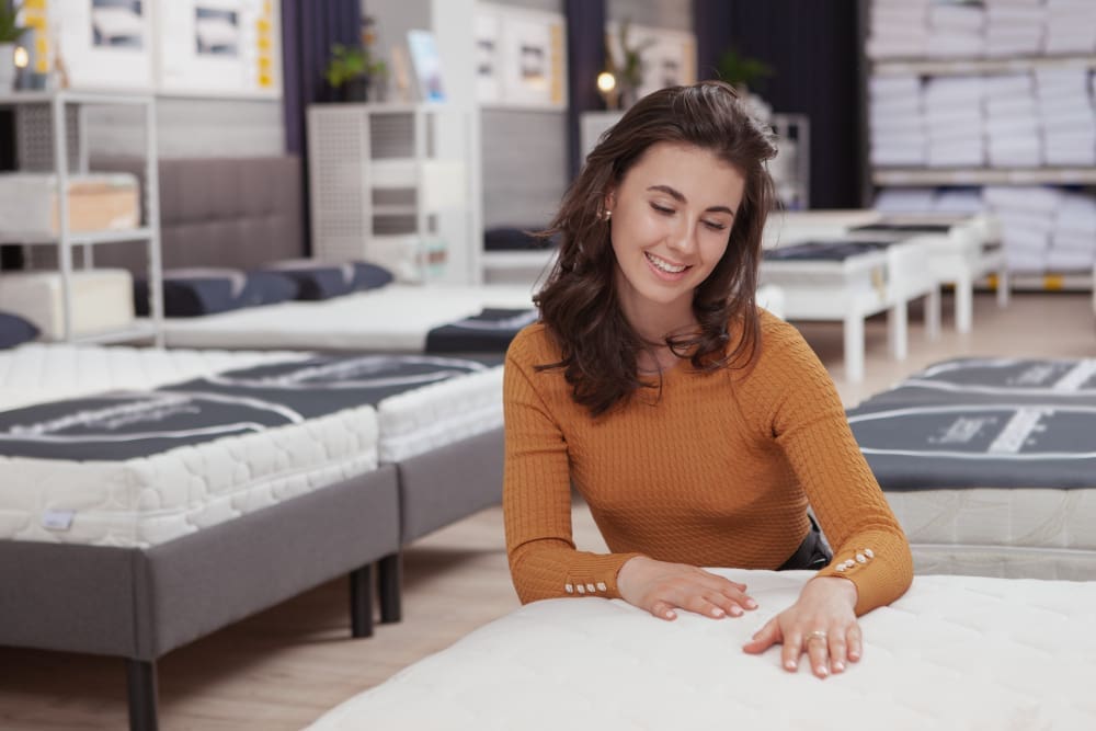 A beautiful young woman is shopping for a mattress
