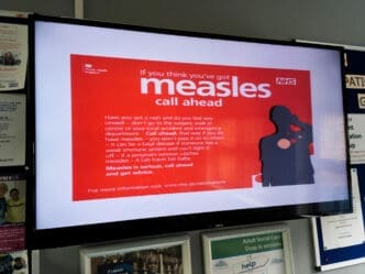 A sign warning people about measles in a NHS doctors surgery clinic