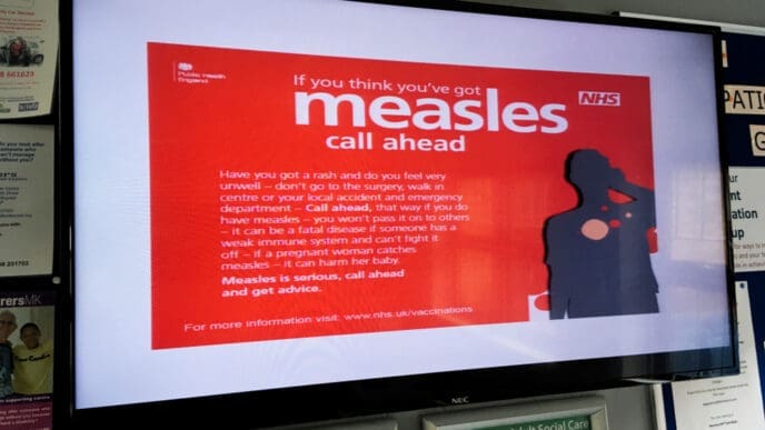 A sign warning people about measles in a NHS doctors surgery clinic