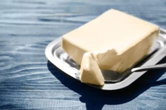 Dish with butter and shovel on wooden table closeup