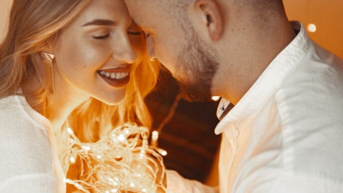 Elegant couple sitting with a garland at home on a bed