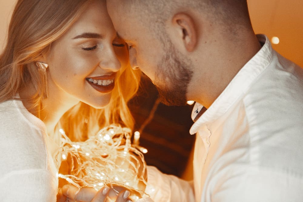 Elegant couple sitting with a garland at home on a bed