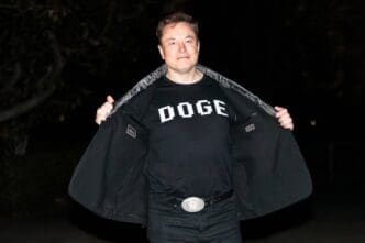 Elon Musk reveals a DOGE t-shirt and a Tesla belt buckle before entering the White House