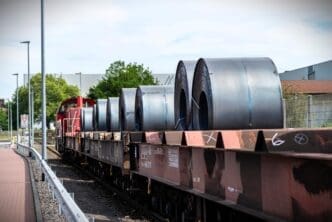 Large rolls of sheet metal lying on a freight wagon pulled by locomotives