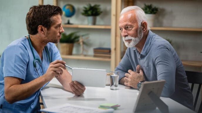 Male doctor using touchpad and explaining medical test results to his senior patient during medical appointment
