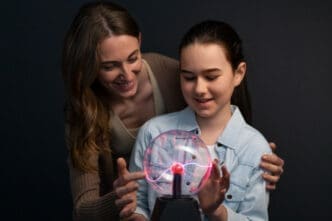 Medium shot woman and girl interacting with a plasma ball