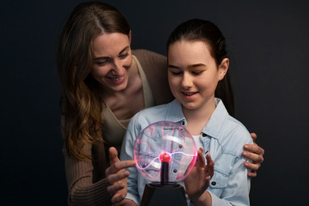Medium shot woman and girl interacting with a plasma ball