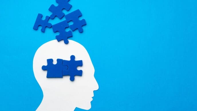 Papercut head with jigsaw puzzle pieces on blue
