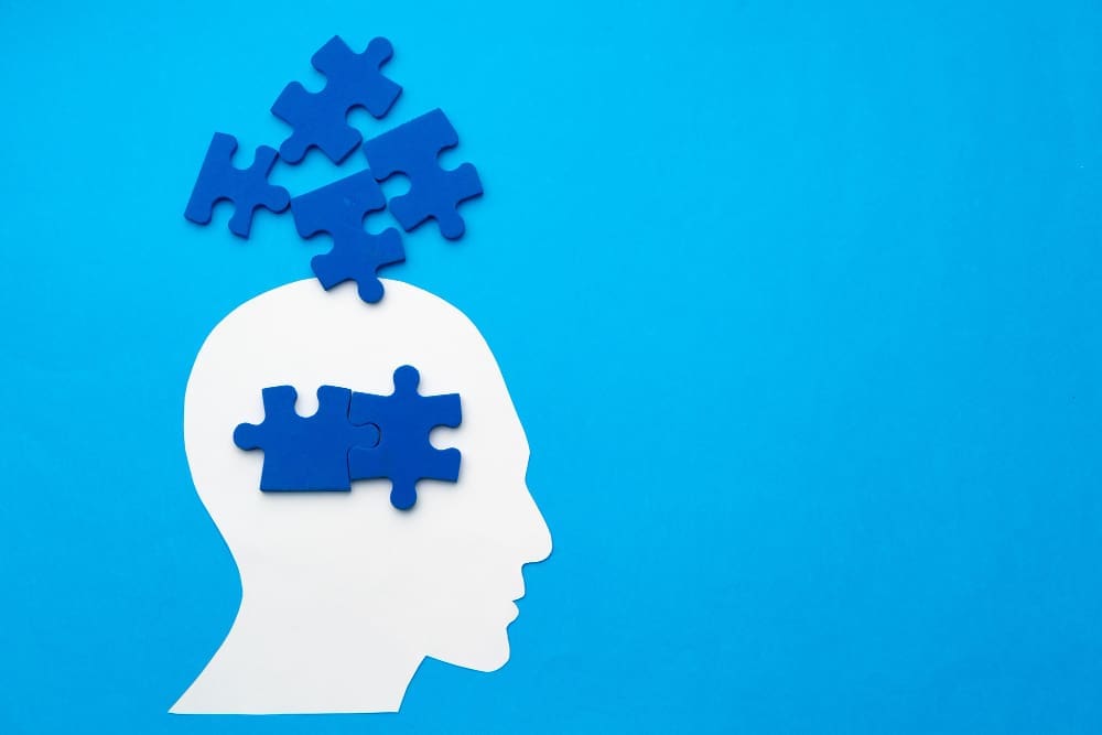 Papercut head with jigsaw puzzle pieces on blue