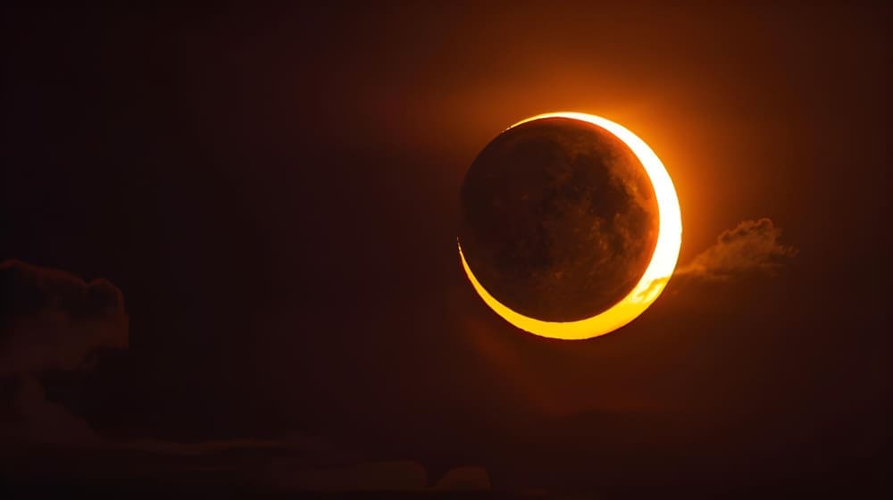 Phenomenon of partial sun eclipse over silhouette orange cloud and sunset sky