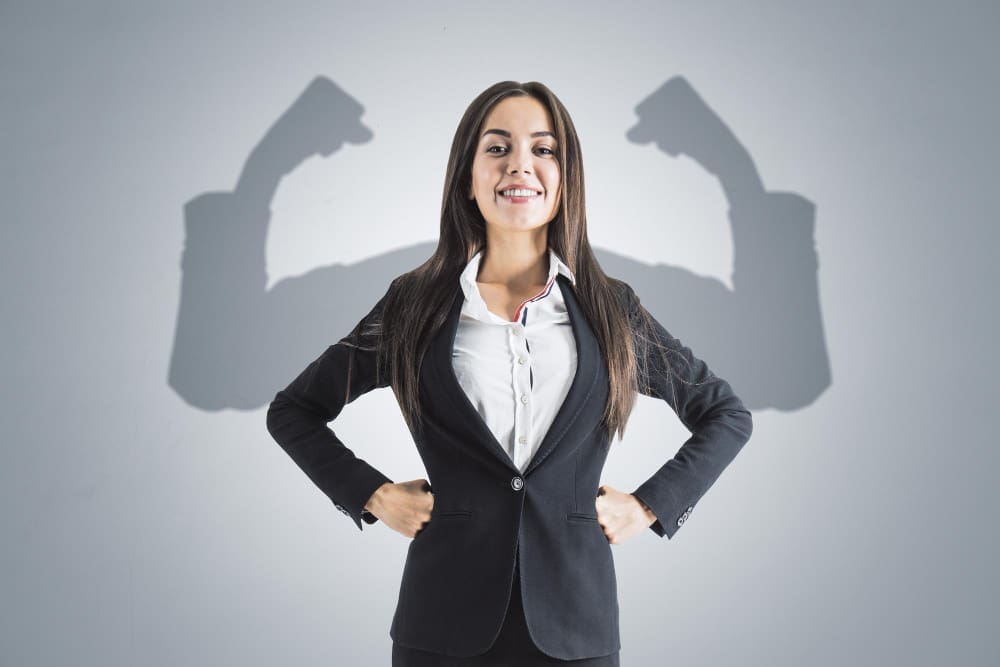 Portrait of an attractive young businesswoman with a smile, hands on her hips, showcasing her well-defined arms