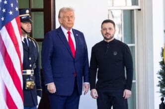 President Donald Trump and Ukrainian President Volodymyr Zelenskyy standing side-by-side at the White House, with a military guard and US flag.