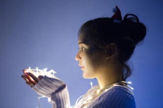 Side view of an introverted, beautiful young woman with lights in her hands