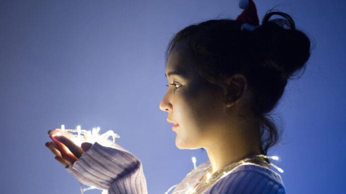 Side view of an introverted, beautiful young woman with lights in her hands