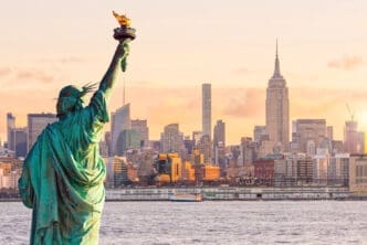 Statue Liberty and New York city skyline at sunset, in United States.