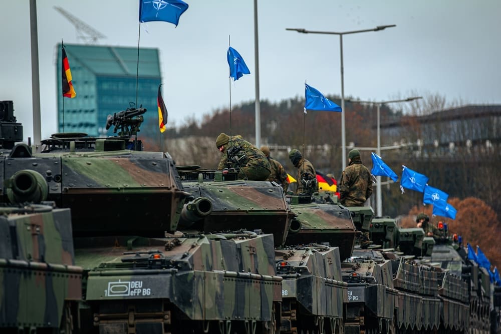 Vilnius, Lithuania - 11 25 2023: A column of German armored vehicles during NATO parade. High-quality photo. Waving NATO flags.
