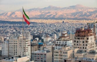 Waving Iran flag above skyline of Tehran at sunset. By Shutterstock.com - Borna_Mirahmadian