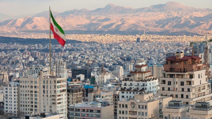 Waving Iran flag above skyline of Tehran at sunset. By Shutterstock.com - Borna_Mirahmadian