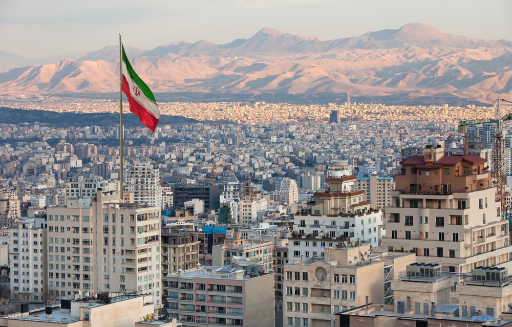 Waving Iran flag above skyline of Tehran at sunset. By Shutterstock.com - Borna_Mirahmadian