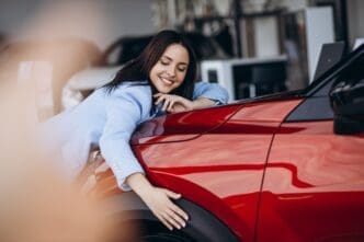 Woman hugging her new red car. By Shutterstock.com - PH888