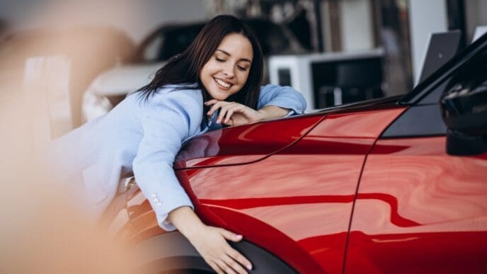 Woman hugging her new red car. By Shutterstock.com - PH888