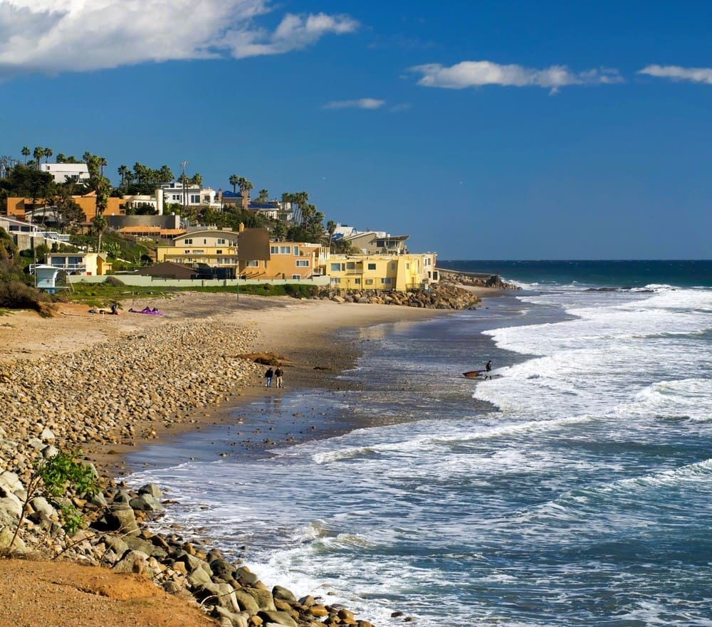 A beautiful vista of County Line Beach in Malibu, with surfers, waves and beautiful houses in the background