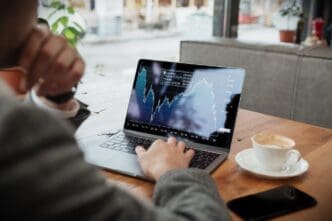 A businessman is sitting at a table in a café, analyzing stock market fluctuations