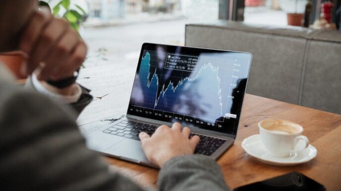 A businessman is sitting at a table in a café, analyzing stock market fluctuations