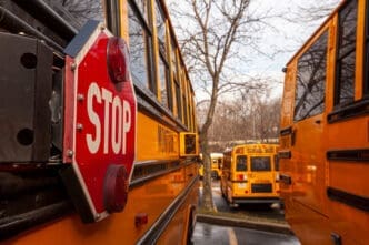 A close up image of yellow American school bus with selective focus on the stop sign on the side. By Shutterstock - Grandbrothers