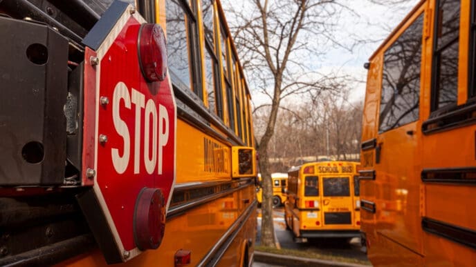 A close up image of yellow American school bus with selective focus on the stop sign on the side. By Shutterstock - Grandbrothers