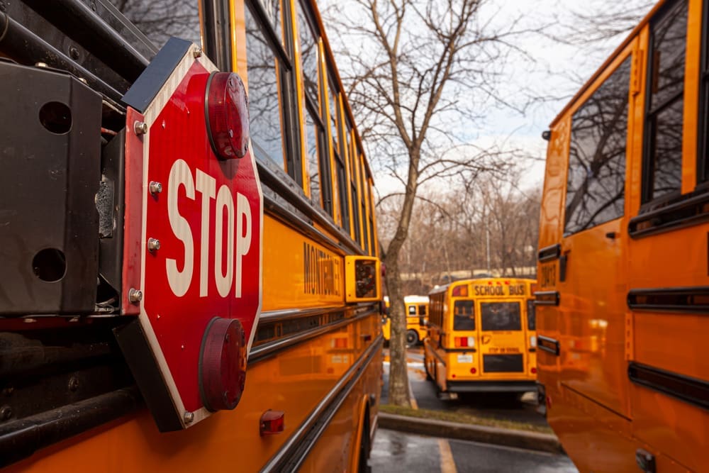 A close up image of yellow American school bus with selective focus on the stop sign on the side. By Shutterstock - Grandbrothers