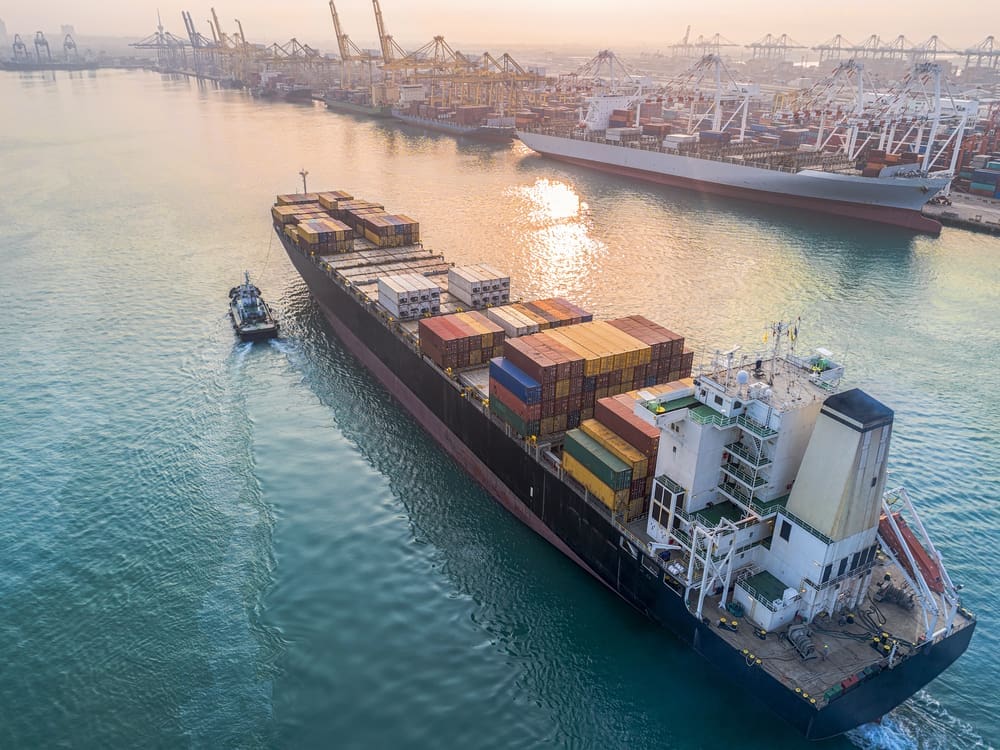 A container ship is arriving at the port, guided by tugboats for a safe entry into the international logistics gateway. By Shutterstock - Iam_Anuphone