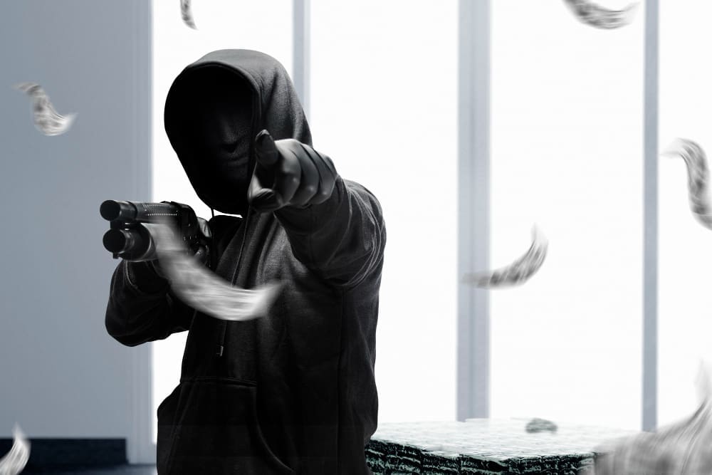 A masked criminal brandished a shotgun, aiming it threateningly at the scene as he demanded compliance during the robbery