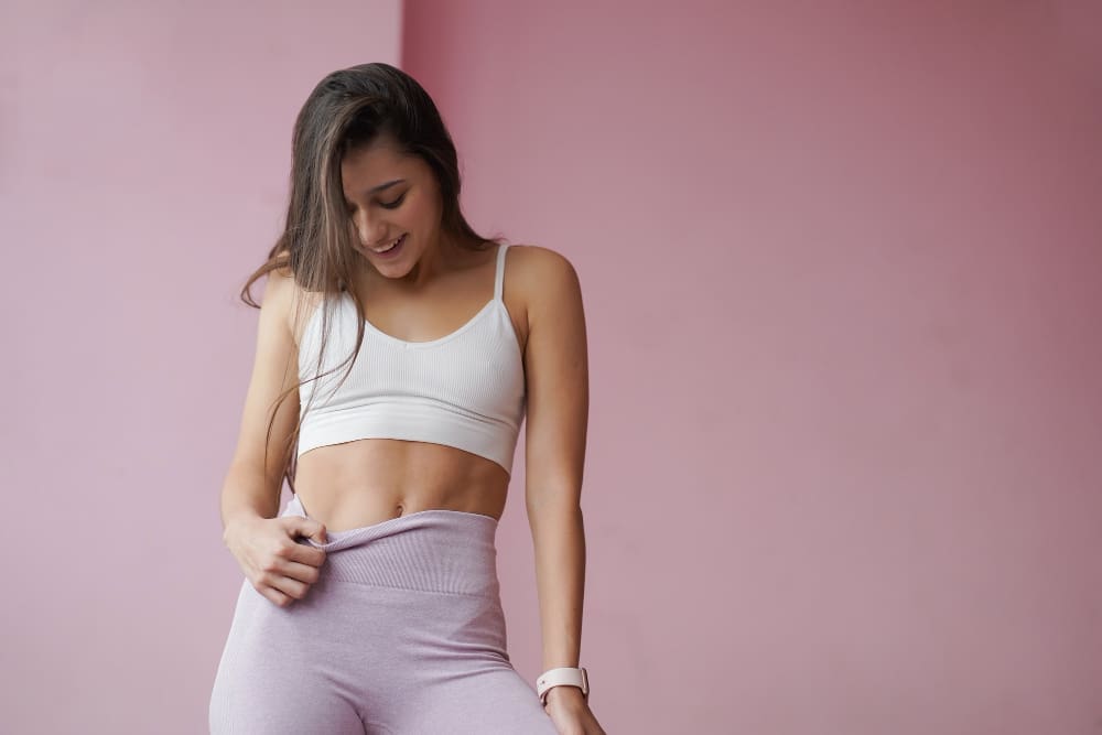 A slim, beautiful woman admires her abs