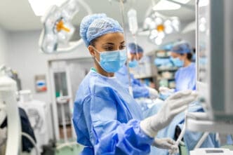 A young female doctor in scrubs and a protective face mask gets ready for surgery