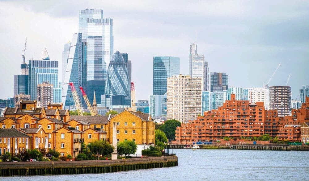 Cityscape of London, UK, featuring the Thames River with a backdrop of financial and residential buildings