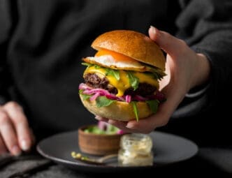 Front view person holding a delicious burger