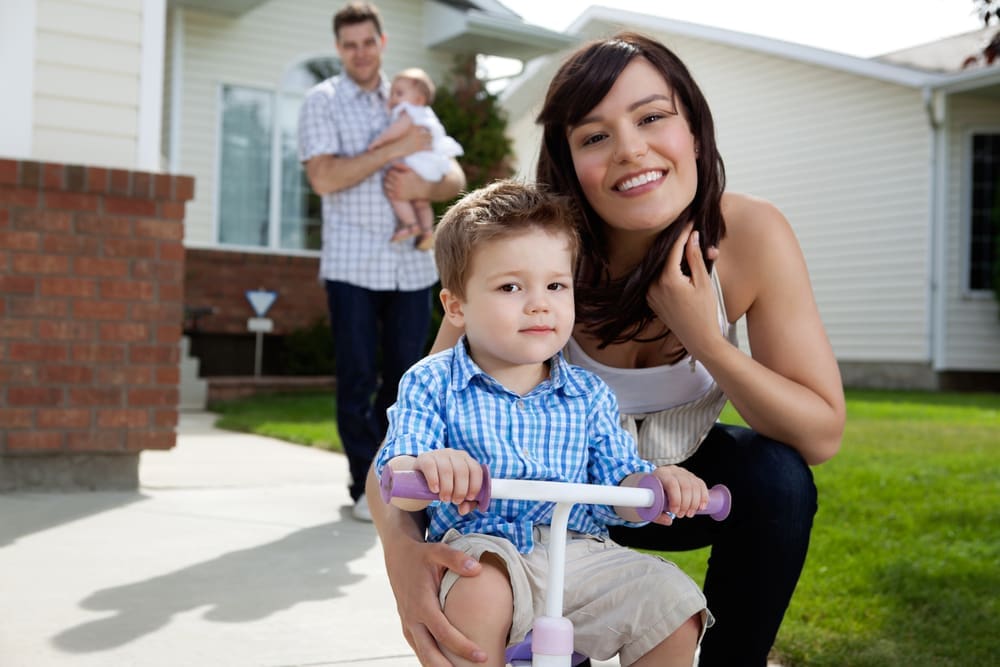 Portrait of happy family with house in background. By Shutterstock.com - Tyler Olson