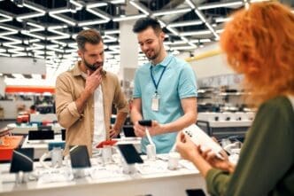 Sales consultant advises man who chooses new smartphone in store of household appliances, electronics and gadgets. By Shutterstock - ORION PRODUCTION