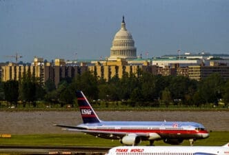 The US Capital dome is visible in the background as seen from Ronald Reagan National Airport with the Potomac River behind the US Airways jet on it's take off roll. By Shutterstock - Mark Reinstein