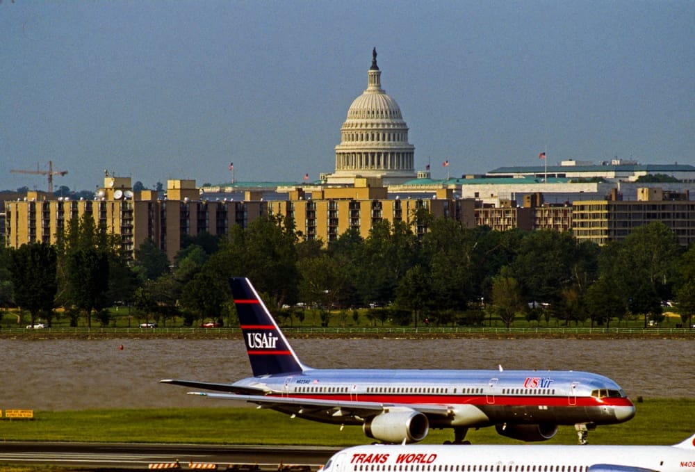 The US Capital dome is visible in the background as seen from Ronald Reagan National Airport with the Potomac River behind the US Airways jet on it's take off roll. By Shutterstock - Mark Reinstein