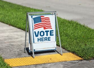 Vote Here Sign placed on the walkway to a neighborhood polling place, as seen on election day in Fort Lauderdale, Florida. By Shutterstock.com - Jillian Cain Photography