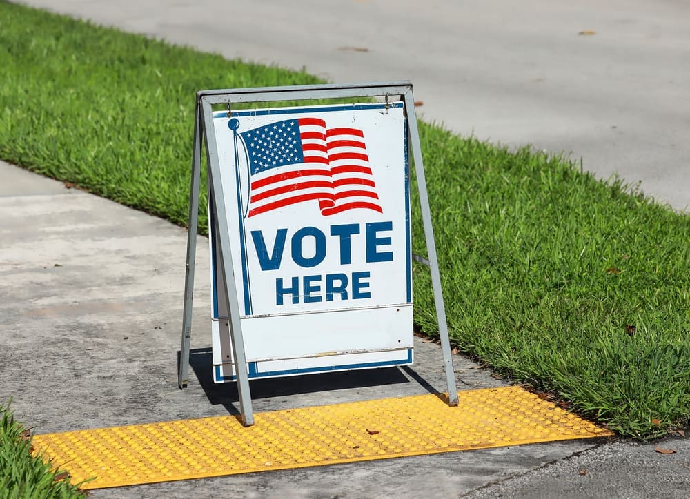 Vote Here Sign placed on the walkway to a neighborhood polling place, as seen on election day in Fort Lauderdale, Florida. By Shutterstock.com - Jillian Cain Photography