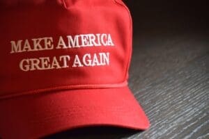 Indianapolis, IN - March 2, 2020. A Donald J. Trump Make America Great Again hat staged on a wooden table from the 2020 Presidential campaign. By Shutterstock - Shelby Griffith